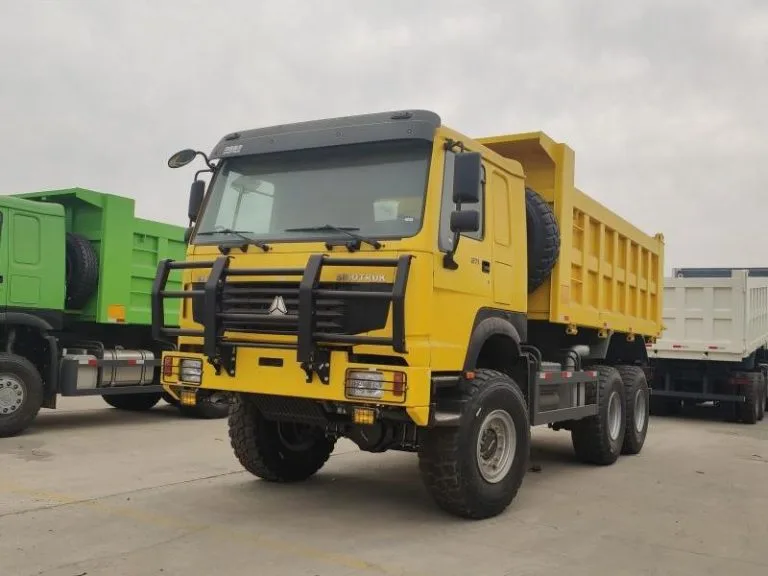 Camião basculante HOWO 6X6 amarelo estacionado num parque, mostrando a sua robusta grelha frontal e faróis com uma grelha de proteção.