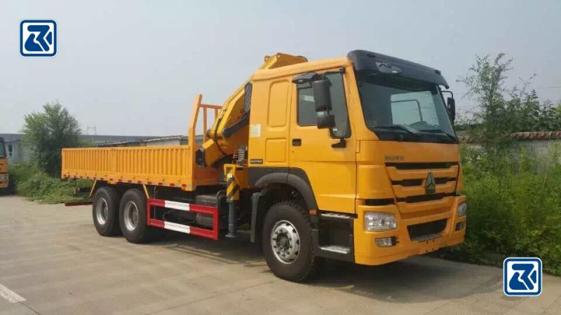 Vista lateral de um robusto camião-grua Howo 6x4, destacando a sua espaçosa área de carga e a avançada tecnologia de grua